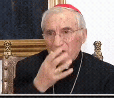 A Man Wearing Glasses And A Red Hat Is Sitting In A Chair Covering His Mouth With His Hand . GIF