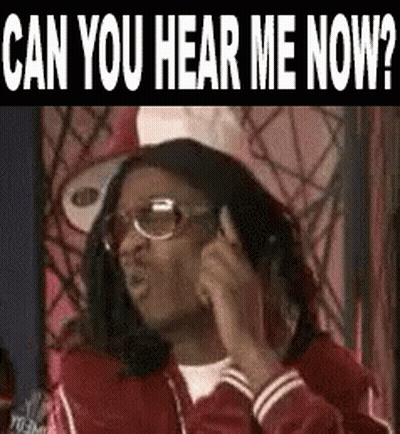 A Man Wearing Glasses And A Red Jacket Is Talking On A Cell Phone And Asking Can You Hear Me Now . GIF