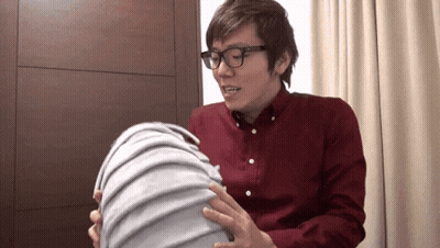 A Man Wearing Glasses And A Red Shirt Is Holding A Large Object GIF