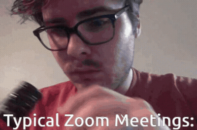 A Man Wearing Glasses And A Red Shirt Is Holding A Microphone With The Words Typical Zoom Meetings Below Him GIF