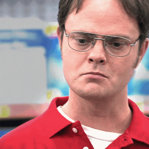 A Man Wearing Glasses And A Red Shirt Is Looking At The Camera GIF