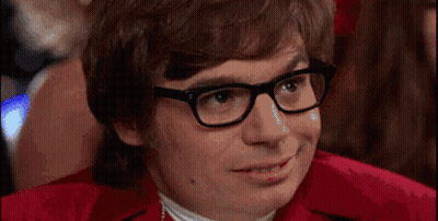 A Man Wearing Glasses And A Red Shirt Is Smiling And Looking At The Camera . GIF