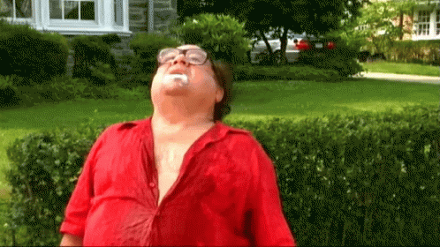 A Man Wearing Glasses And A Red Shirt Is Standing In Front Of A House With His Mouth Open .. GIF