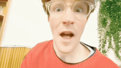 A Man Wearing Glasses And A Red Sweater Makes A Funny Face GIF