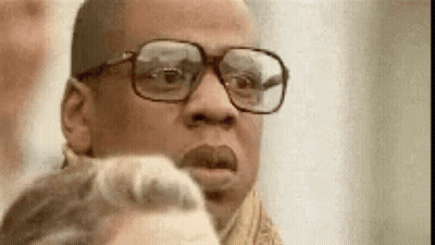 A Man Wearing Glasses And A Scarf Is Looking At A Woman . GIF