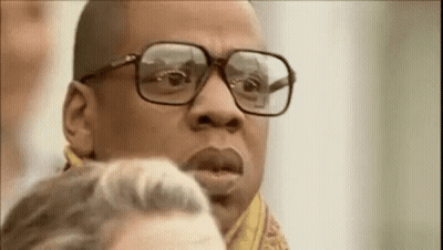 A Man Wearing Glasses And A Scarf Is Looking At Something . GIF