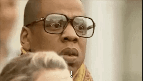 A Man Wearing Glasses And A Scarf Is Making A Funny Face . GIF
