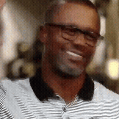 A Man Wearing Glasses And A Striped Shirt Is Laughing . GIF