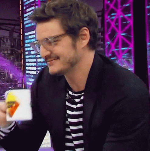 A Man Wearing Glasses And A Striped Shirt Is Smiling While Holding A Bag Of Chips GIF