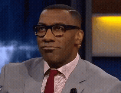 A Man Wearing Glasses And A Suit And Tie Is Looking At The Camera . GIF