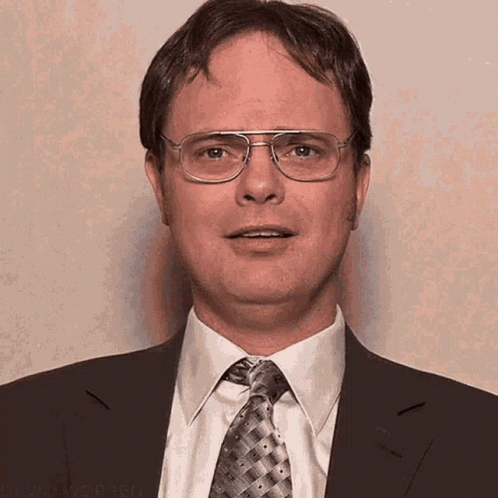 A Man Wearing Glasses And A Suit And Tie Is Smiling GIF