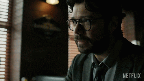 A Man Wearing Glasses And A Suit Has A Netflix Logo On His Sleeve GIF