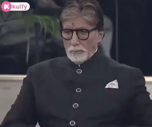 A Man Wearing Glasses And A Suit Is Clapping His Hands Together . GIF