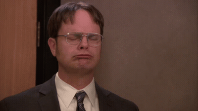 A Man Wearing Glasses And A Suit Is Making A Face GIF