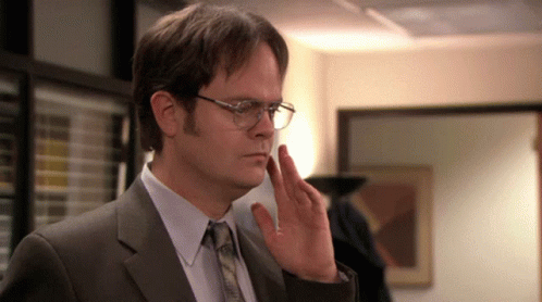 A Man Wearing Glasses And A Suit Is Making A Gesture With His Hand GIF