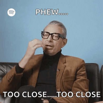 A Man Wearing Glasses And A Suit Is Sitting On A Couch And Says Phew Too Close Too Close . GIF