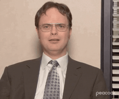 A Man Wearing Glasses And A Suit Is Standing In Front Of A Piano Keyboard . GIF