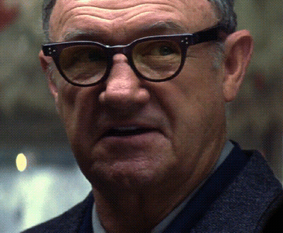 A Man Wearing Glasses And A Suit Looks At The Camera GIF