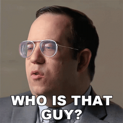 A Man Wearing Glasses And A Suit Says " Who Is That Guy " GIF