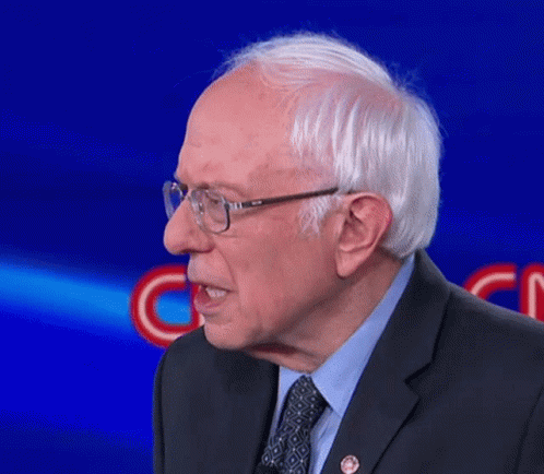 A Man Wearing Glasses And A Suit Stands In Front Of A Blue Background That Says Cnn GIF