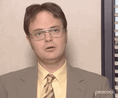 A Man Wearing Glasses And A Suit With Peacock Written On The Bottom Right GIF