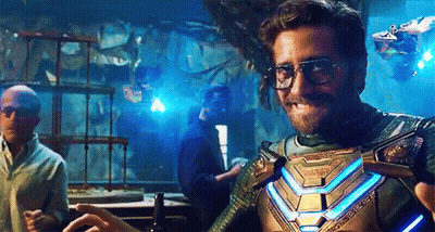 A Man Wearing Glasses And A Superhero Costume Is Standing In A Room With Other Men . GIF