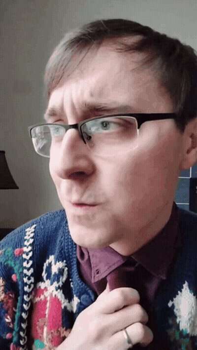 A Man Wearing Glasses And A Sweater Has A Ring On His Left Hand GIF