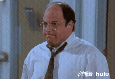 A Man Wearing Glasses And A Tie Has A Seinfeld Hulu Advertisement Behind Him GIF