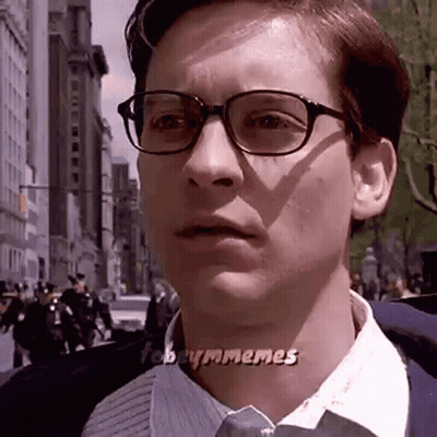 A Man Wearing Glasses And A Tie Is Looking At The Camera . GIF