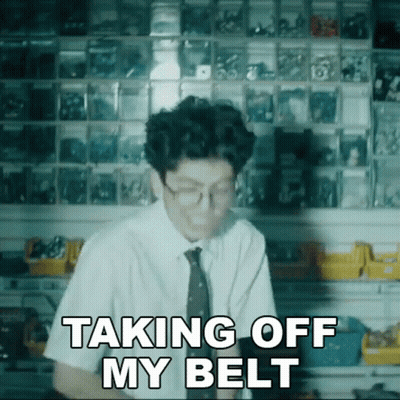A Man Wearing Glasses And A Tie Says " Taking Off My Belt " GIF