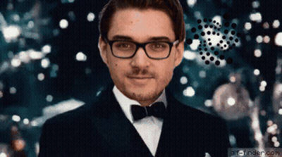 A Man Wearing Glasses And A Tuxedo Is Standing In Front Of A Christmas Tree .. GIF
