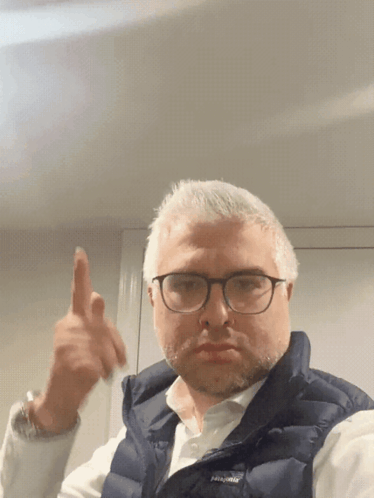 A Man Wearing Glasses And A Vest That Says Patagonia GIF