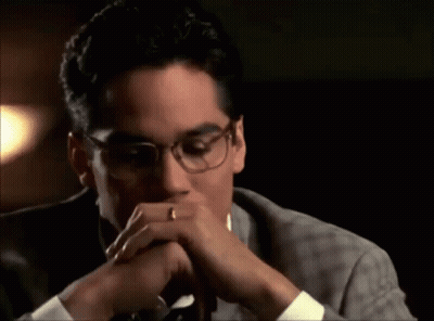 A Man Wearing Glasses And A Wedding Ring Is Covering His Mouth With His Hands . GIF