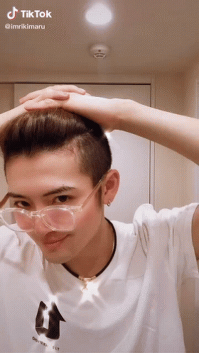 A Man Wearing Glasses And A White Shirt Has A Tiktok Sticker On His Head GIF