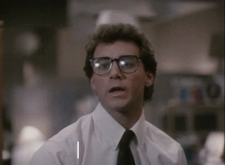 A Man Wearing Glasses And A White Shirt Is Looking At The Camera GIF