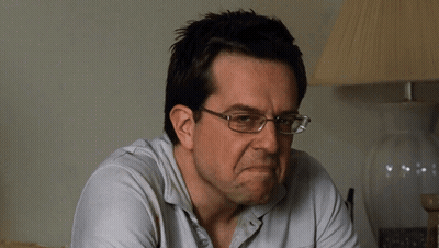 A Man Wearing Glasses And A White Shirt Is Making A Face GIF