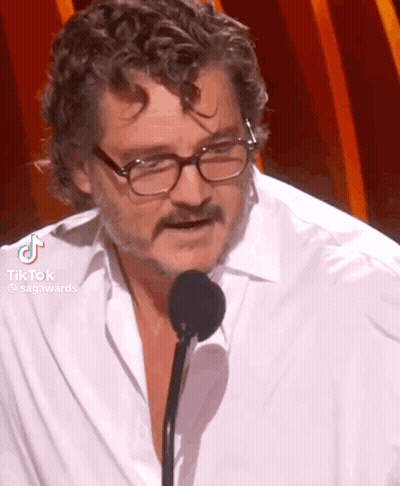 A Man Wearing Glasses And A White Shirt Is Speaking Into A Microphone . GIF