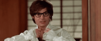 A Man Wearing Glasses And A White Shirt Is Standing In Front Of A Window . GIF