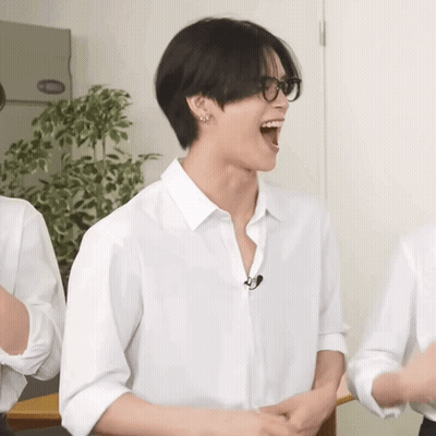 A Man Wearing Glasses And A White Shirt Laughs With His Mouth Open GIF