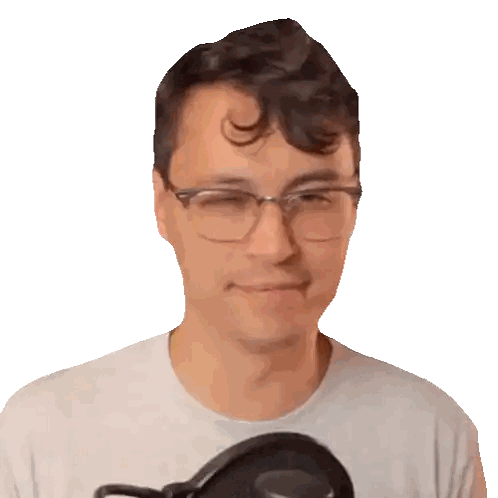 A Man Wearing Glasses And A White Shirt Smiles In Front Of A Microphone Sticker