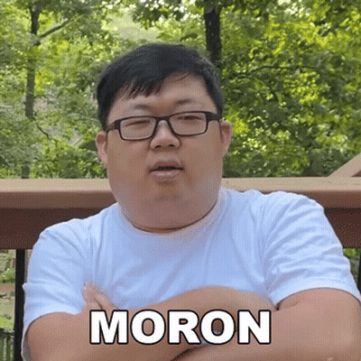 A Man Wearing Glasses And A White Shirt With The Word Moron On His Chest GIF