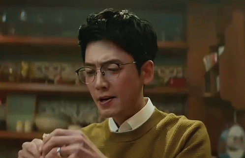 A Man Wearing Glasses And A Yellow Sweater Is Holding His Nose GIF