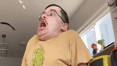 A Man Wearing Glasses And A Yellow T-Shirt With A Dinosaur On It GIF
