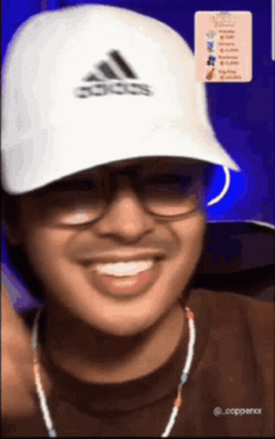 A Man Wearing Glasses And An Adidas Hat Smiles GIF
