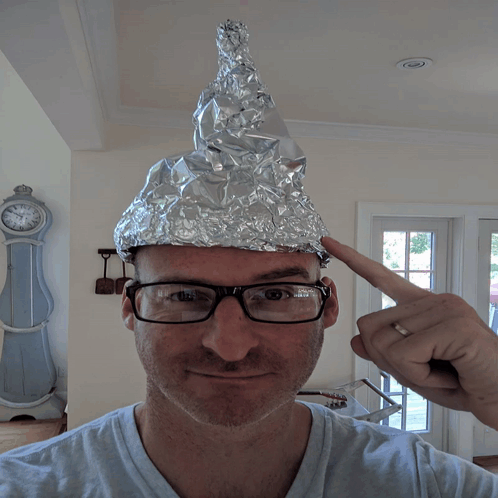 A Man Wearing Glasses And An Aluminum Foil Cone On His Head GIF