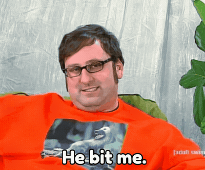 A Man Wearing Glasses And An Orange Shirt That Says He Bit Me On It GIF