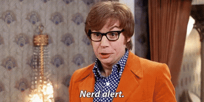 A Man Wearing Glasses And An Orange Suit Is Standing In A Room And Says Nerd Alert . GIF
