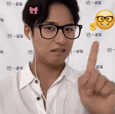 A Man Wearing Glasses And Ear Buds Is Pointing His Finger GIF