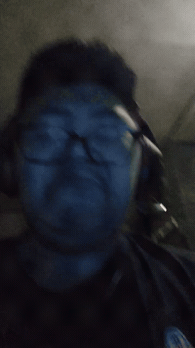 A Man Wearing Glasses And Headphones Is Looking At The Camera GIF