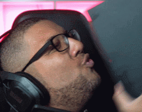A Man Wearing Glasses And Headphones Is Looking Down GIF